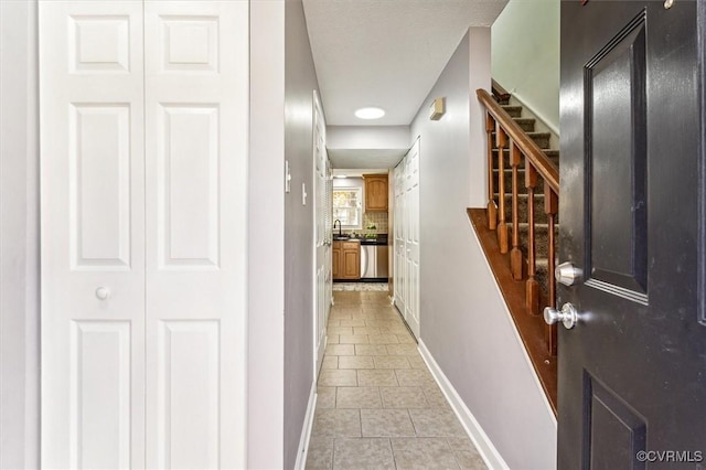 hall featuring sink and light tile patterned flooring