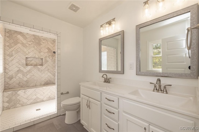 bathroom featuring tile patterned floors, toilet, vanity, and tiled shower