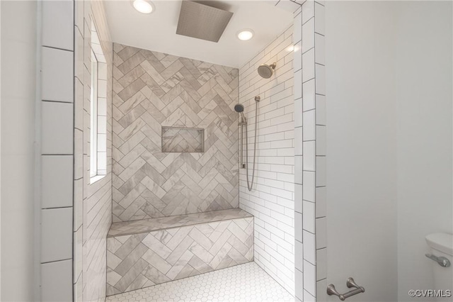 bathroom featuring tiled shower and toilet