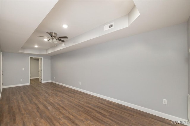 unfurnished room with dark hardwood / wood-style floors, ceiling fan, and a tray ceiling