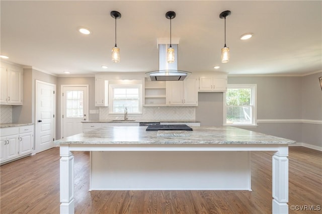 kitchen with tasteful backsplash, island range hood, sink, white cabinets, and a large island