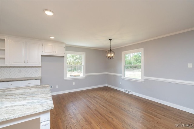 kitchen with pendant lighting, backsplash, white cabinets, crown molding, and light stone countertops