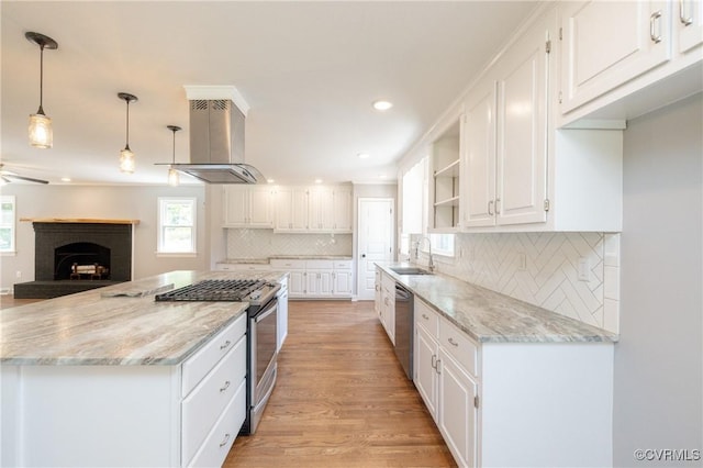 kitchen featuring sink, wall chimney exhaust hood, hanging light fixtures, white cabinets, and appliances with stainless steel finishes