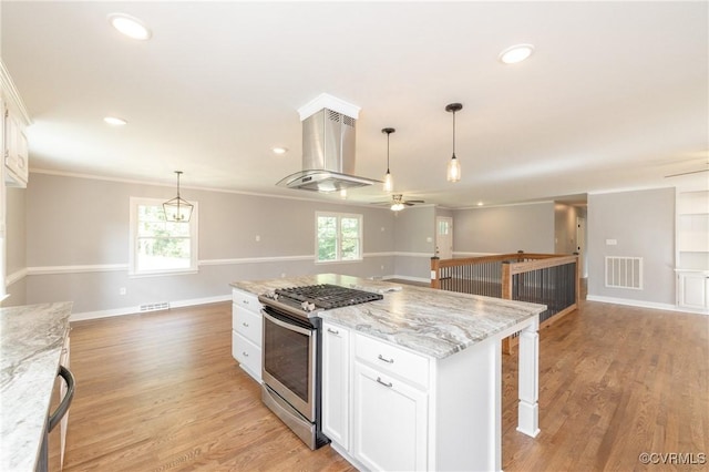 kitchen featuring ceiling fan, stainless steel gas range oven, light stone counters, ventilation hood, and white cabinets