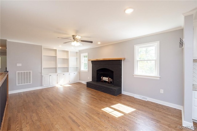 unfurnished living room with a brick fireplace, ceiling fan, light hardwood / wood-style floors, and ornamental molding