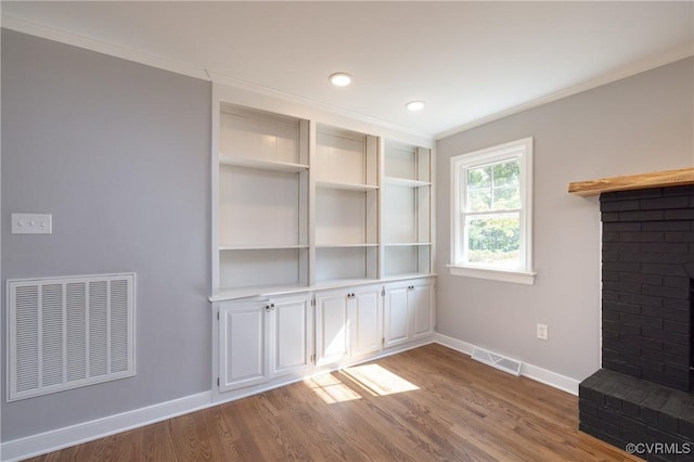 unfurnished living room with a fireplace, hardwood / wood-style flooring, and crown molding