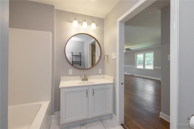 bathroom with ceiling fan, a washtub, and vanity