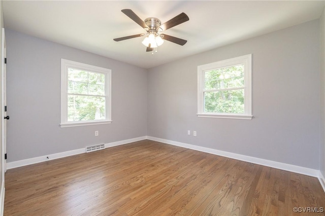 spare room featuring a wealth of natural light, ceiling fan, and wood-type flooring