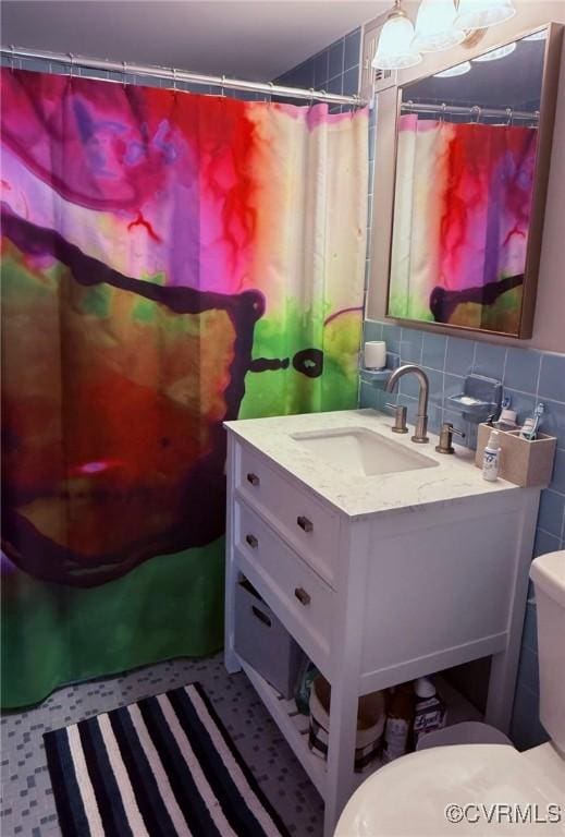 bathroom with vanity, toilet, tile walls, and tasteful backsplash