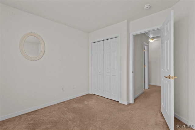 unfurnished bedroom with light colored carpet and a closet