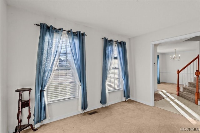 carpeted empty room with a notable chandelier