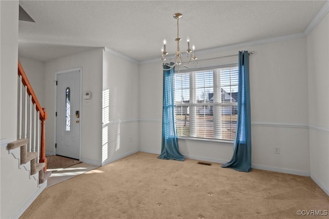 entryway featuring carpet, ornamental molding, a textured ceiling, and an inviting chandelier