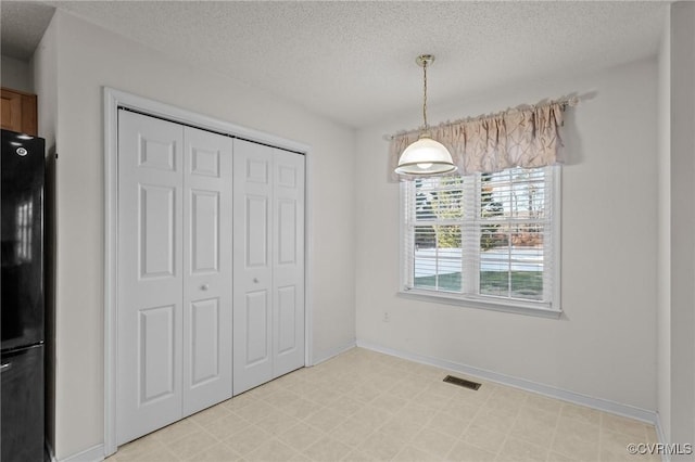 unfurnished dining area with a textured ceiling