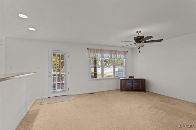 spare room featuring ceiling fan, a healthy amount of sunlight, and light carpet