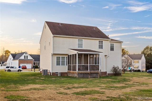 back house at dusk featuring a yard, central AC, a garage, and a sunroom