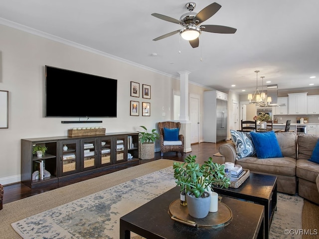 living room with ceiling fan with notable chandelier, dark wood-type flooring, crown molding, and ornate columns