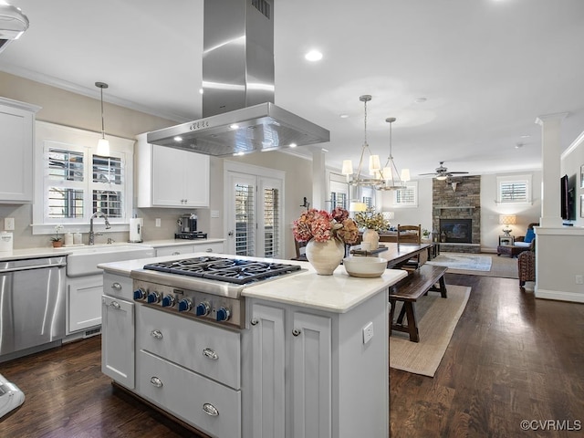 kitchen featuring stainless steel appliances, island exhaust hood, white cabinetry, a fireplace, and ceiling fan