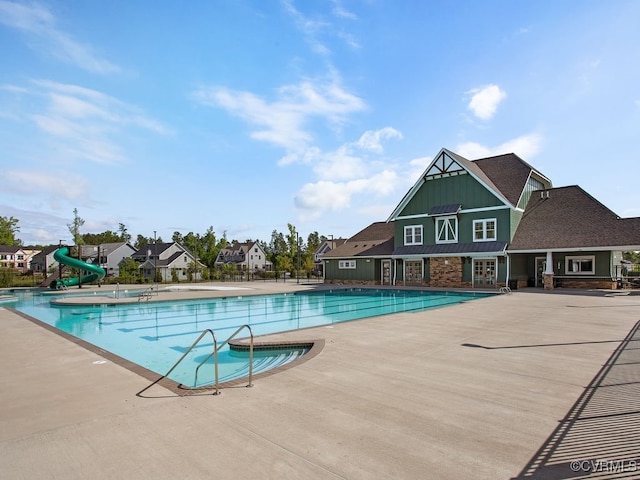 view of swimming pool featuring a water slide, a patio area, and a playground