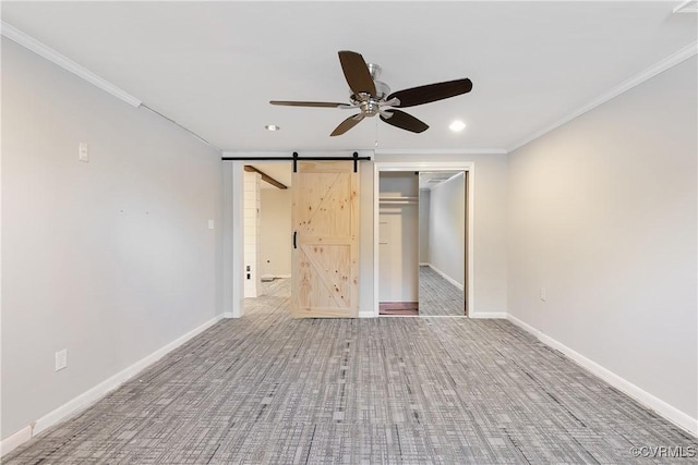 unfurnished bedroom featuring ceiling fan, a barn door, a closet, and ornamental molding