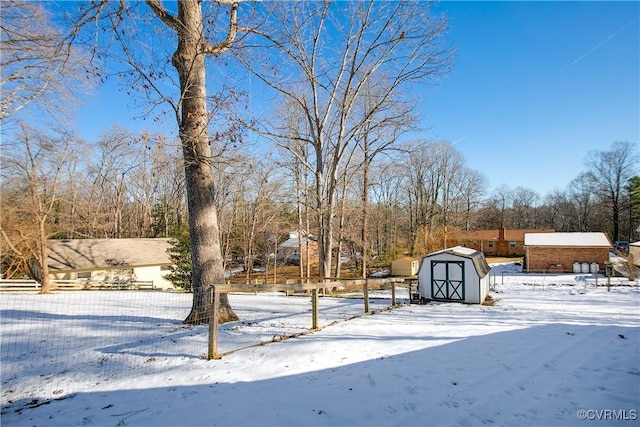 snowy yard featuring a storage shed