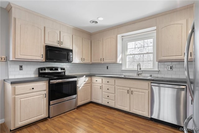 kitchen featuring stainless steel appliances, decorative backsplash, light hardwood / wood-style flooring, and sink