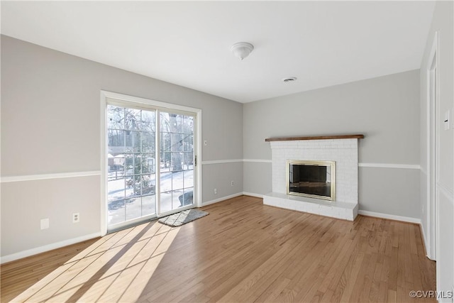 unfurnished living room with a brick fireplace and light hardwood / wood-style floors