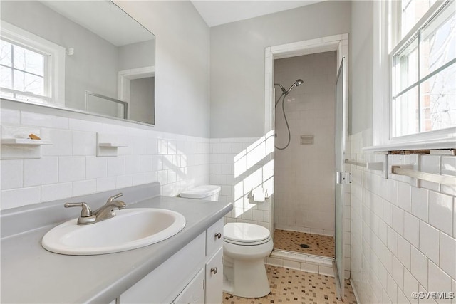 bathroom featuring tile patterned flooring, vanity, tile walls, toilet, and walk in shower