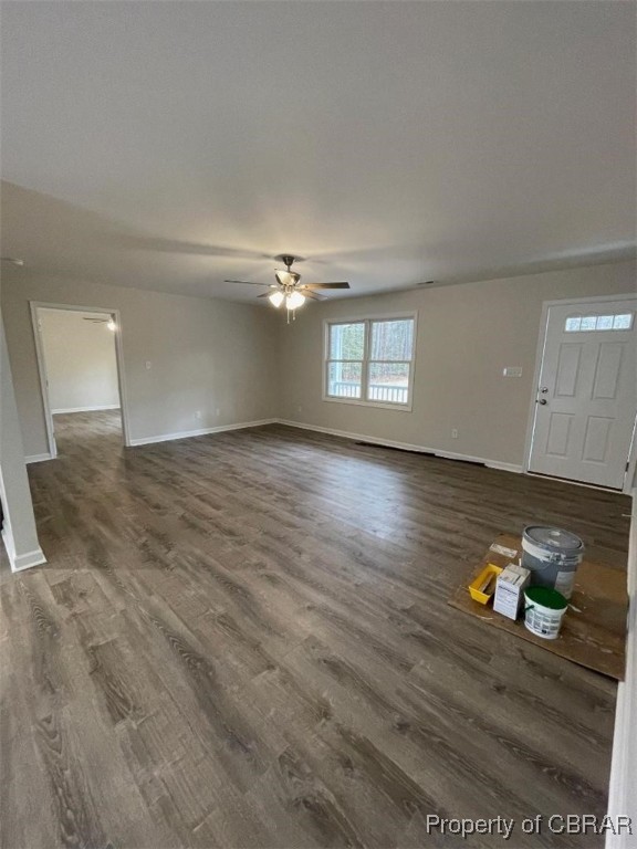 unfurnished living room with ceiling fan and dark wood-type flooring