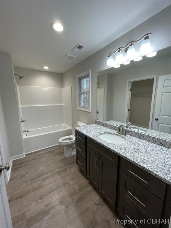 full bathroom with washtub / shower combination, vanity, hardwood / wood-style flooring, and toilet