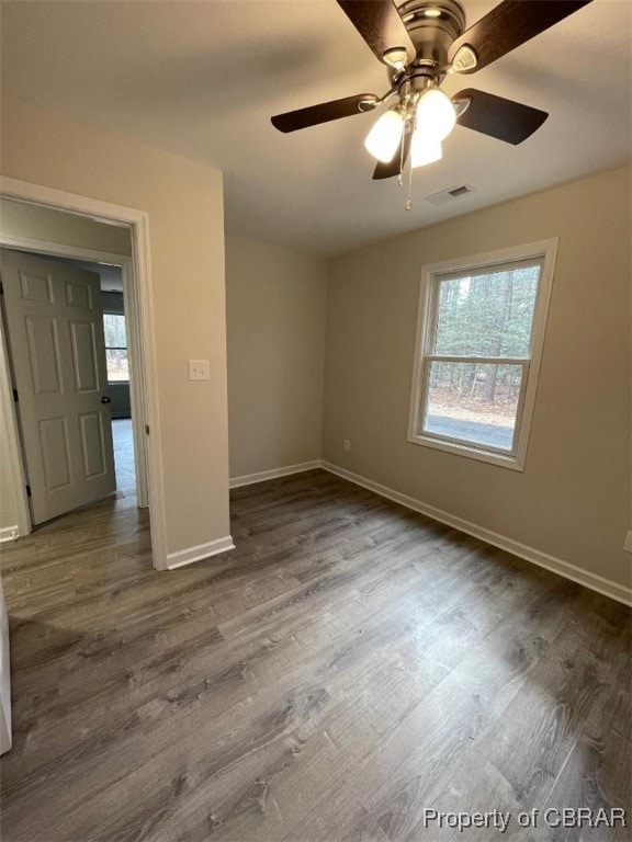 spare room featuring ceiling fan, a healthy amount of sunlight, and dark hardwood / wood-style floors