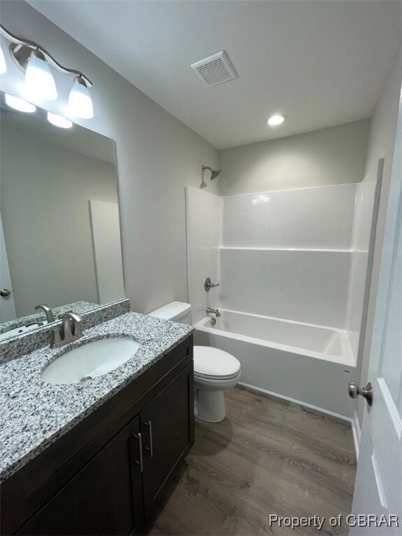 full bathroom featuring vanity, shower / bath combination, hardwood / wood-style flooring, and toilet