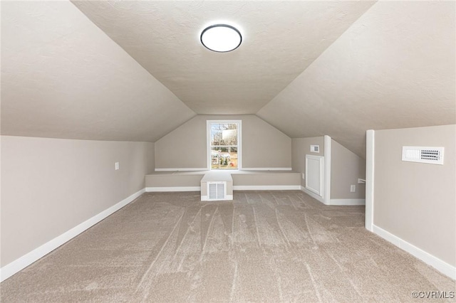 additional living space with lofted ceiling, carpet floors, and a textured ceiling