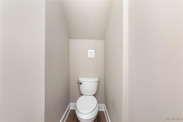 bathroom featuring toilet, wood-type flooring, and vaulted ceiling