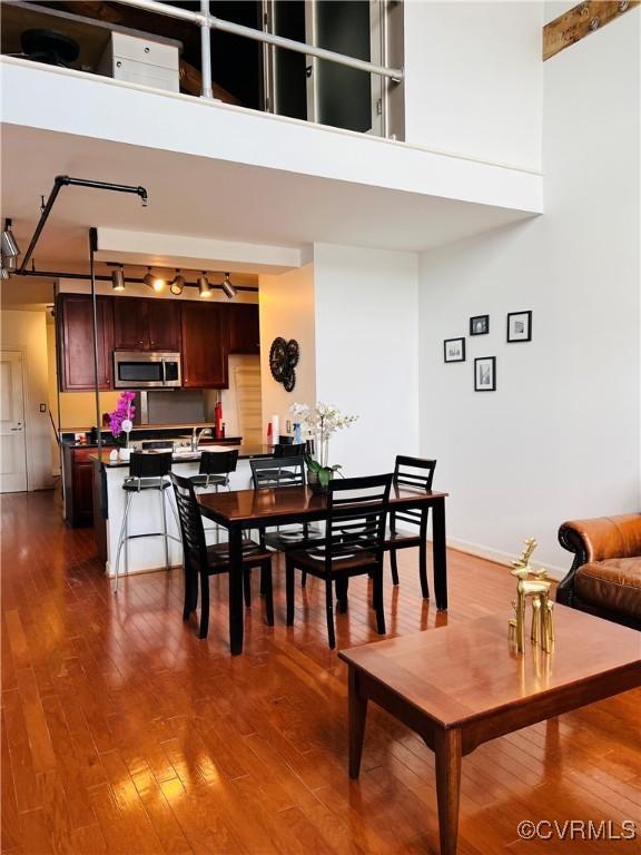 dining area featuring a towering ceiling and dark wood-type flooring