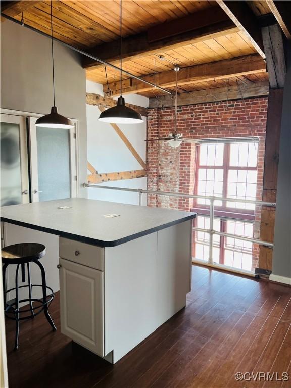 kitchen featuring wooden ceiling, hanging light fixtures, beamed ceiling, a kitchen island, and white cabinetry