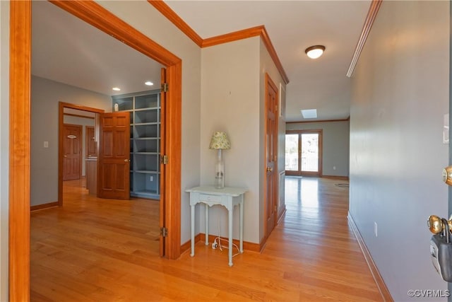 hall with built in shelves, light wood-type flooring, crown molding, and french doors