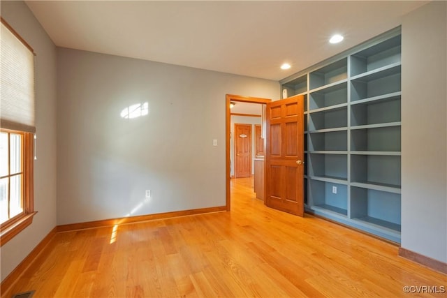 empty room with built in features and light hardwood / wood-style flooring