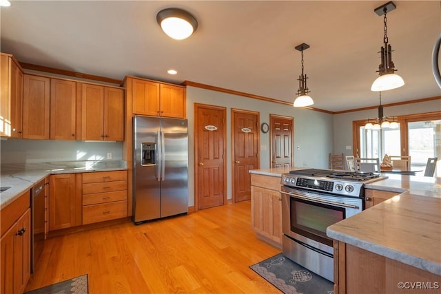 kitchen featuring crown molding, hanging light fixtures, stainless steel appliances, and light wood-type flooring