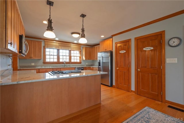 kitchen featuring decorative light fixtures, sink, kitchen peninsula, and stainless steel appliances