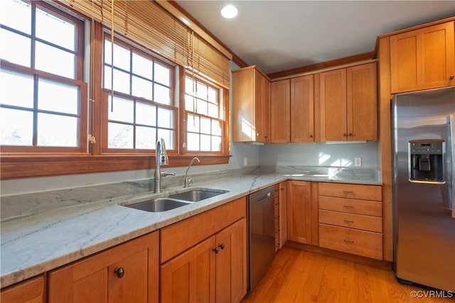 kitchen with light stone countertops, sink, light hardwood / wood-style floors, and appliances with stainless steel finishes