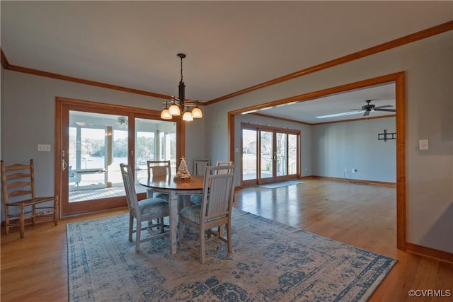 dining space with crown molding, light hardwood / wood-style floors, and ceiling fan with notable chandelier