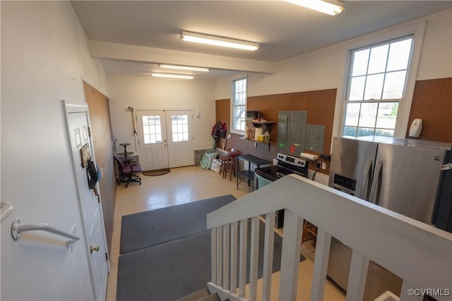 interior space featuring concrete flooring, french doors, stainless steel refrigerator with ice dispenser, and electric range