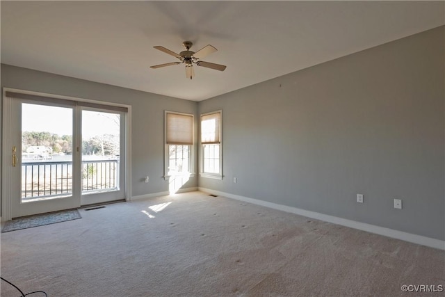 empty room featuring ceiling fan, a water view, and light colored carpet