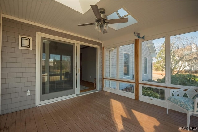 unfurnished sunroom with ceiling fan, a wealth of natural light, and a skylight