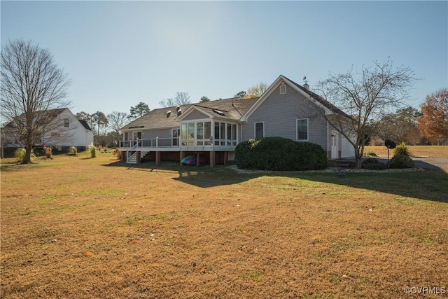 rear view of house featuring a yard, a deck, and a sunroom