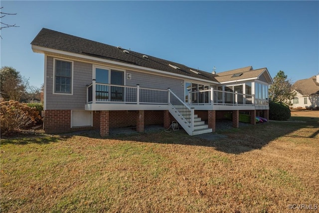 rear view of house featuring a wooden deck, a sunroom, and a yard