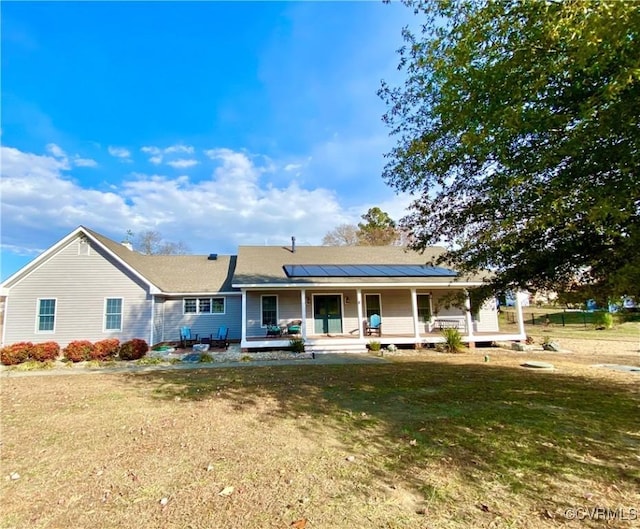 view of front of house featuring covered porch, solar panels, and a front lawn