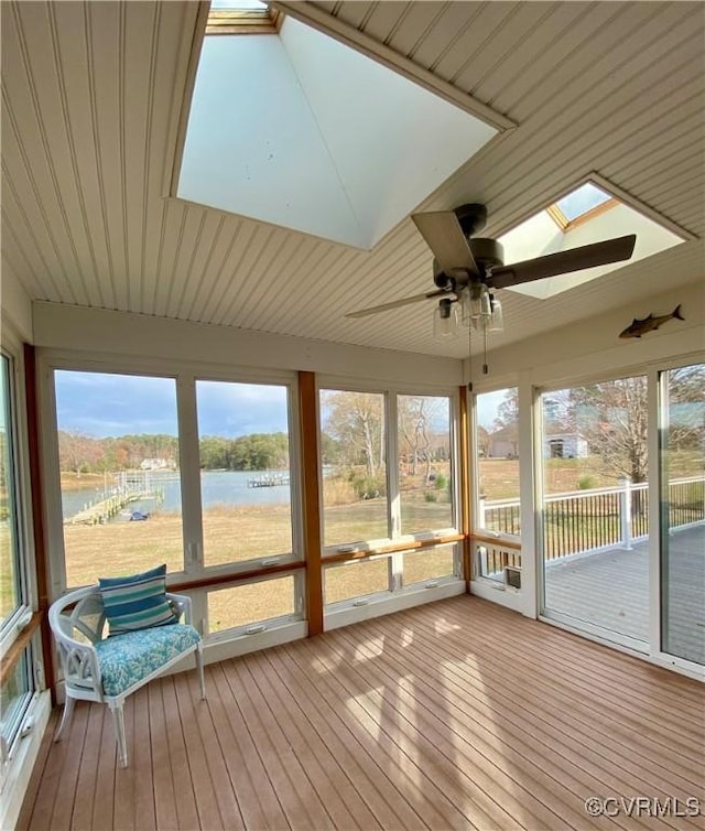 unfurnished sunroom with a skylight, ceiling fan, a water view, and a wealth of natural light