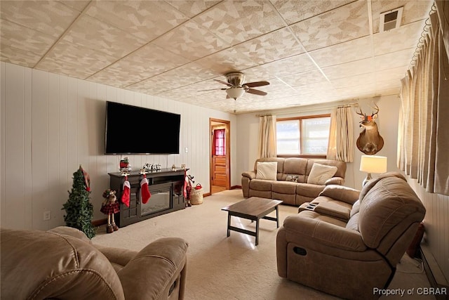 living room featuring ceiling fan, carpet, and wood walls