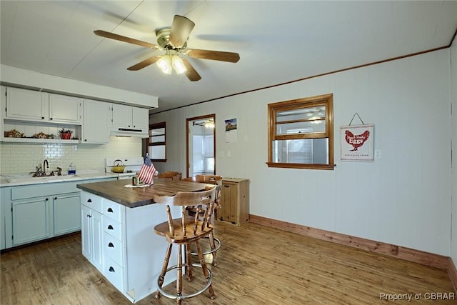 kitchen featuring sink, a kitchen island, white electric range, light hardwood / wood-style flooring, and white cabinets